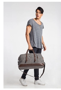 Detail view of large canvas travel bag in grey with brown leather straps and accents