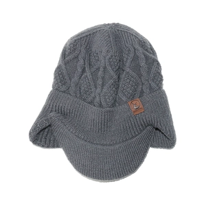 Détail du tricot torsadé et de l'écusson en cuir sur le bonnet d'hiver gris à rabats