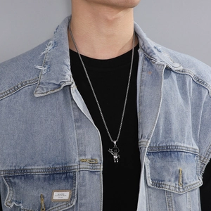 Detail of silver astronaut pendant holding a star worn with denim jacket streetwear style