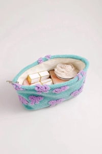 Blue plush makeup bag detail showing soft texture and purple floral bow decorations