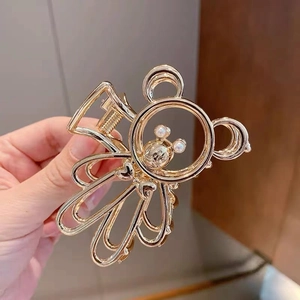 Detail of golden metal teddy bear hair claw clip with pearl accents and hollow design