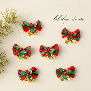 Christmas bow bell decorations with red green ribbons and gold bells on snowy pine branch