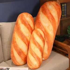 Drei Größen Plüsch-Baguette-Kissen auf einem beigen Sofa in gemütlichem Zimmer
