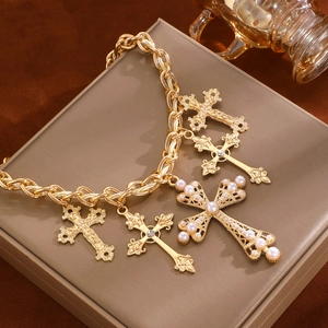Detail of chunky gold chain bracelet with pearl and rhinestone cross pendants on jewelry box