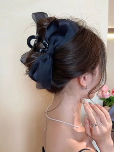 Side view of large black satin bow hair claw clip worn on a sophisticated hair bun