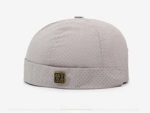 Détail du bonnet docker gris clair avec maille respirante et logo en métal doré