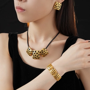 Close-up of vintage gold leopard print jewelry set with earrings, necklace, and bracelet