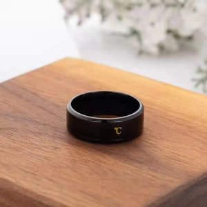 Macro shot of a black temperature-sensing ring with gold Celsius icon on a wooden stand