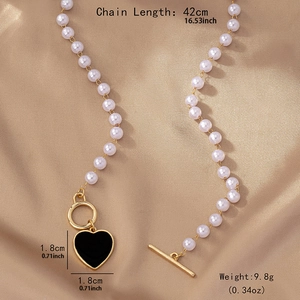 Elegant pearl necklace with black heart pendant and golden toggle clasp on satin