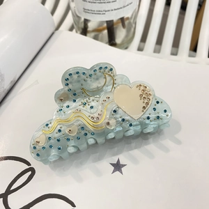 Macro detail of a light blue acetate hair claw clip with rhinestones and golden wavy edges