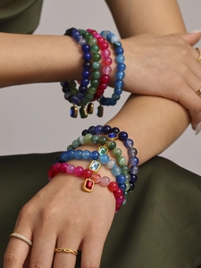 Detail of colorful agate bead bracelets with gold-edged charms on a model's wrist
