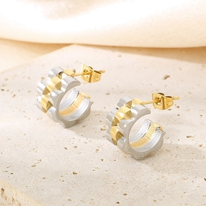Détail de boucles d'oreilles créoles en acier titane bicolore or et argent sur pierre