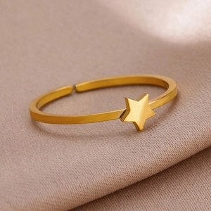 Macro shot of minimalist gold star open ring on textured champagne fabric background