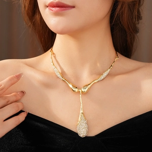 Gros plan d'un collier pendentif goutte dorée avec strass sur le cou d'un mannequin