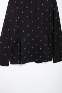 Détail du dos d'un blazer noir avec de délicates broderies de fraises rouges sur le tissu