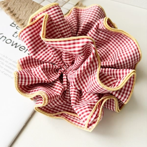 Detailed close-up of an oversized red and white checkered scrunchie with yellow piping trim