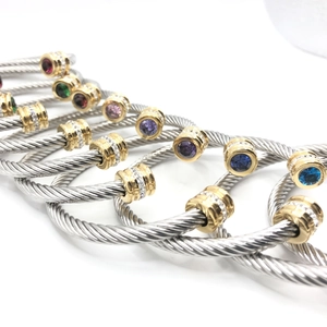 Macro detail of twisted cable bangles in two-tone gold and silver finish with gemstones