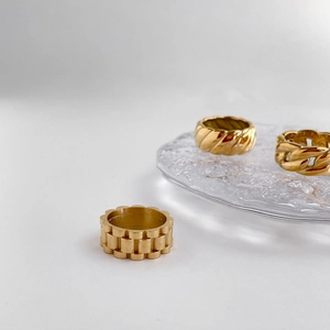 Detailansicht von drei goldfarbenen Kettenringen auf einem Glastablett