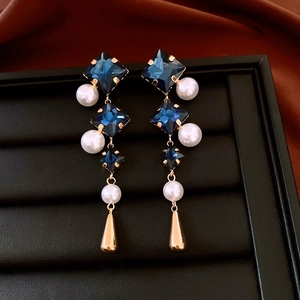 Detail of vintage geometric earrings with blue crystals, pearls, and gold water drop charms