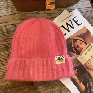 Detail of hot pink fuzzy knit beanie with 1982 California patch on wooden table