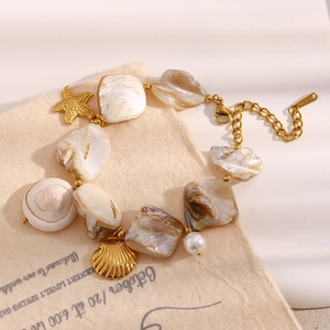 Détail du bracelet avec breloques de coquillages baroques et étoile de mer en acier doré
