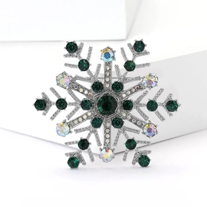 Vue macro d'une broche flocon de neige avec cristaux vert émeraude et base argentée