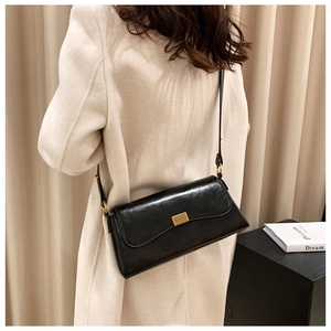 Schicke schwarze Leder-Umhängetasche mit goldener Schnalle an einem Model