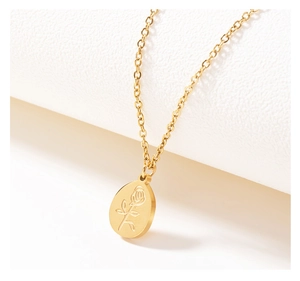 Macro shot of an oval gold pendant featuring a detailed rose engraving on a white background