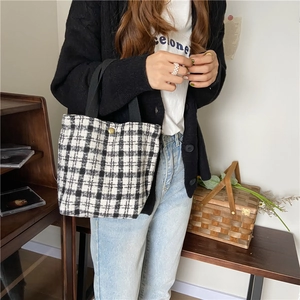 Detail of black and white checkered wool tote bag featuring a vintage gold button closure
