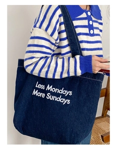 Grand sac cabas en denim bleu foncé avec broderie blanche porté à l'épaule