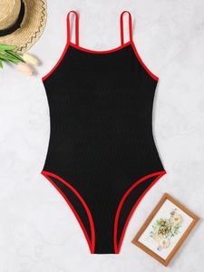 Detailed view of black backless swimsuit with red piping and wavy jacquard texture