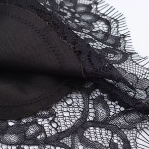 Close-up of elegant black lace trim with delicate eyelash edges on satin dress fabric