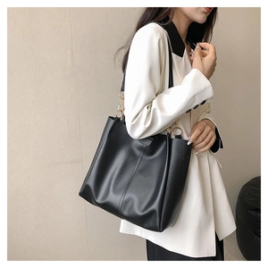 Detail of black soft PU leather tote bag featuring elegant golden chain straps and large capacity