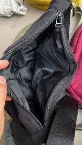 Detail showing internal compartment and spacious main pocket of black nylon crossbody bag