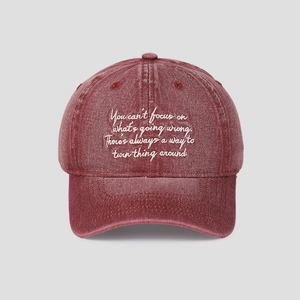 Détail d'une casquette vintage bordeaux délavée avec texte inspirant brodé en blanc pur