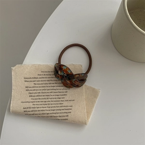 Detailed view of brown tortoiseshell acetate hair scrunchie with FRANCE Handmade engraving