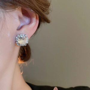Close-up of square silver stud earrings with sparkling cubic zirconia on a female model