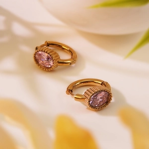 Détail de boucles d'oreilles dorées vintage avec pierres roses et bords texturés