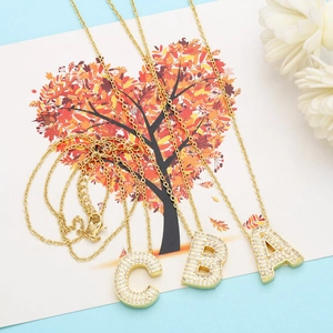Detailed close-up of gold-plated letter A, B, C necklaces with shimmering zircon pavé