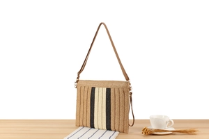 Detail view of woven paper rope shoulder bag with vertical stripes on a wooden table