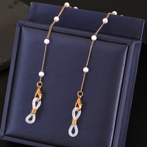 Détail de la chaîne de lunettes dorée avec perles blanches sur velours bleu foncé