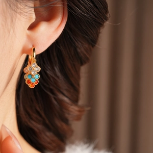 Close-up of vintage gold tassel earrings with zircon flower on female model