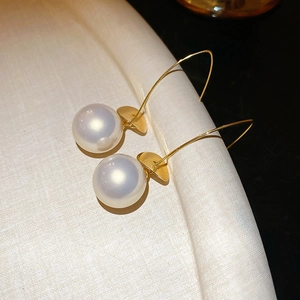 Detail of gold metal hook earrings with round white pearl and sequin charm decor