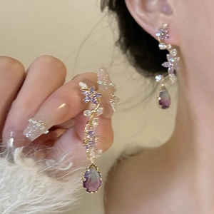 Détail de boucles d'oreilles fleur en cristal violet avec pierre en forme de poire