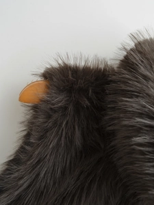 Macro shot of dark faux fur vest texture with orange horn-shaped plastic accessory
