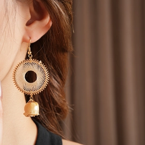 Detail of woven dreamcatcher earrings with preserved flowers worn by a model