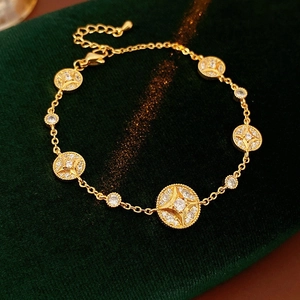 Detailed close-up of 18K gold plated bracelet with starburst zircon charms on green velvet