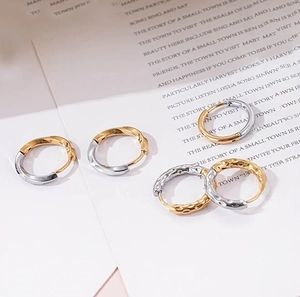 Detail of gold and silver two-tone hoop earrings with twisted and hammered textures