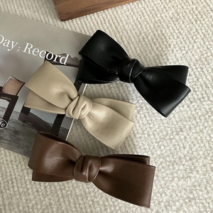 Three PU leather bow hair clips in black, beige, and brown with elegant leather texture