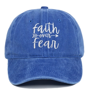 Close-up of white faith over fear embroidery on washed blue cotton baseball cap